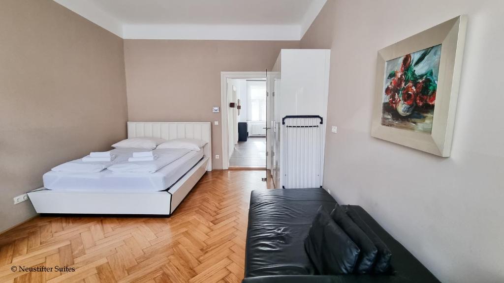 ein Schlafzimmer mit einem Bett und einem schwarzen Ledersofa in der Unterkunft Appartement Cervantes 13 in Wien