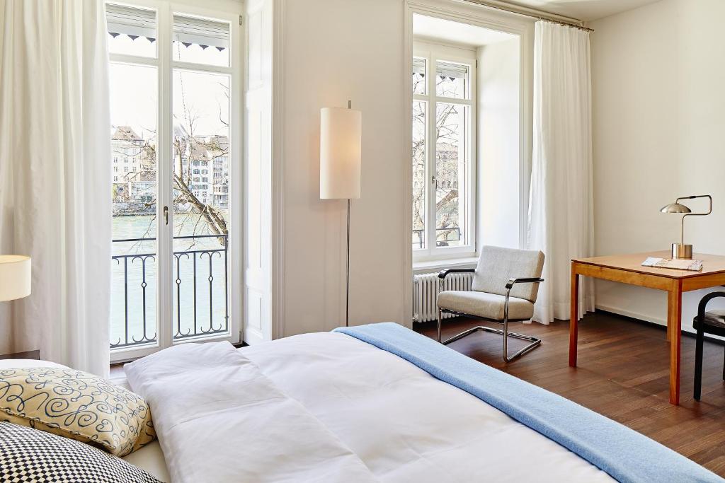 a bedroom with a bed and a desk and windows at Krafft Basel in Basel