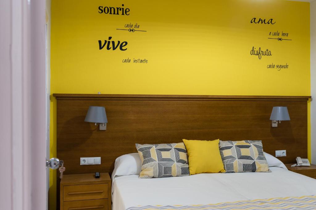 1 dormitorio con 1 cama con pared amarilla en Hostal Imperial, en Mérida