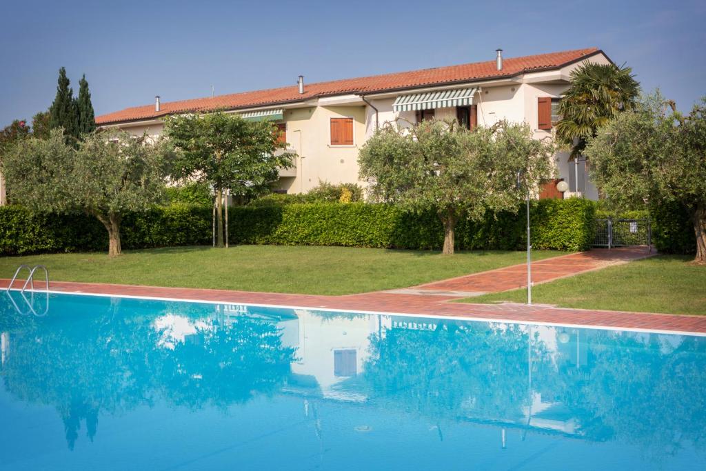 a blue swimming pool in front of a house at Appartamento al Sole in Colà di Lazise