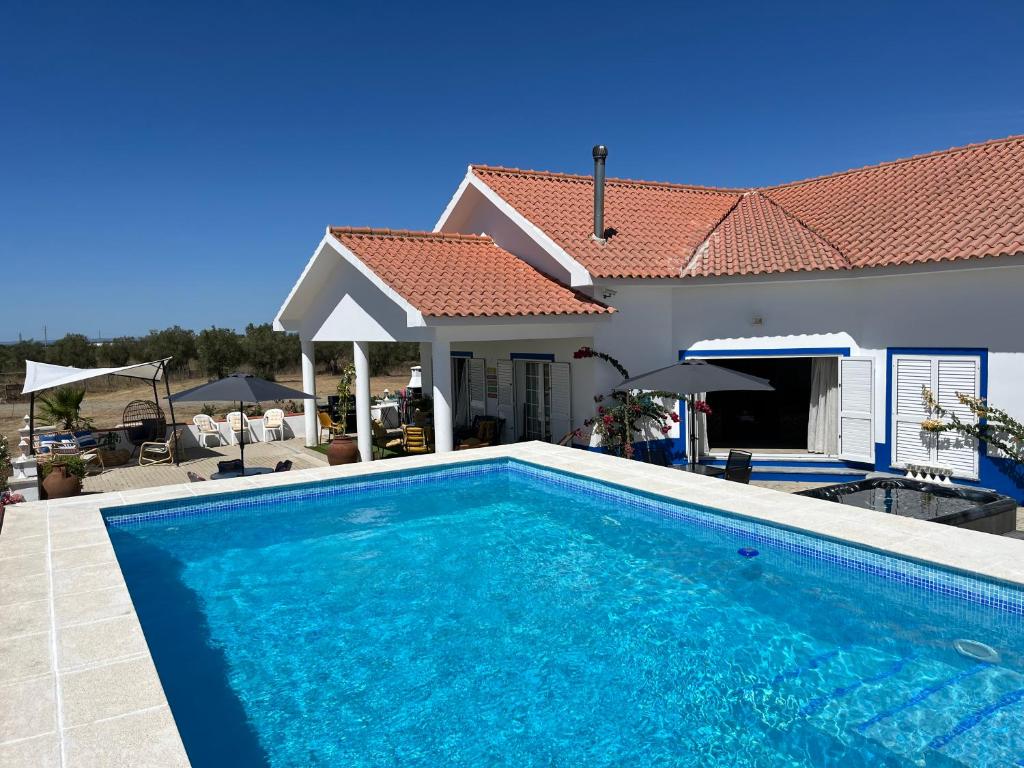 a swimming pool in front of a house at Quinta Da Amoreira in Ferreira do Alentejo