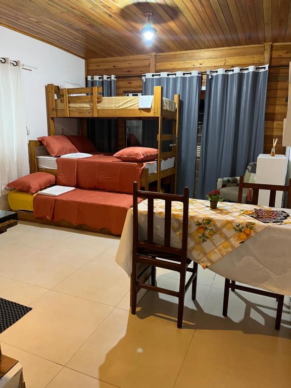 a room with two bunk beds and a table and chair at Canto Gira Sol - Estúdio Sol - Térreo in Penha
