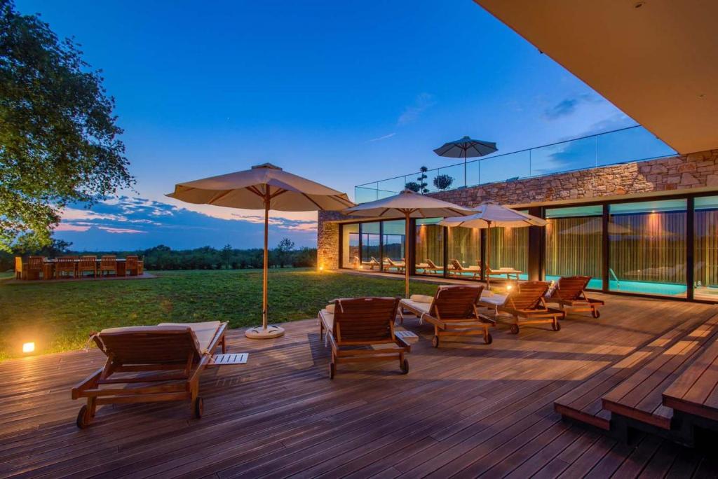 une terrasse avec des chaises et des parasols sur une maison dans l'établissement Villa Novica Platinum - 4 Bedroom Villa - Rural Countryside setting - Jacuzzi Sauna and Gym, à Jasenovica