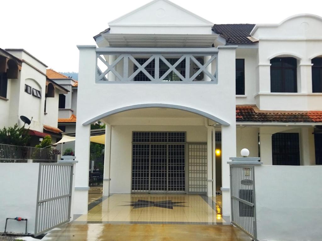 una casa blanca con una puerta delante de ella en Pinang Beach Home @ Ferringhi, en Batu Ferringhi