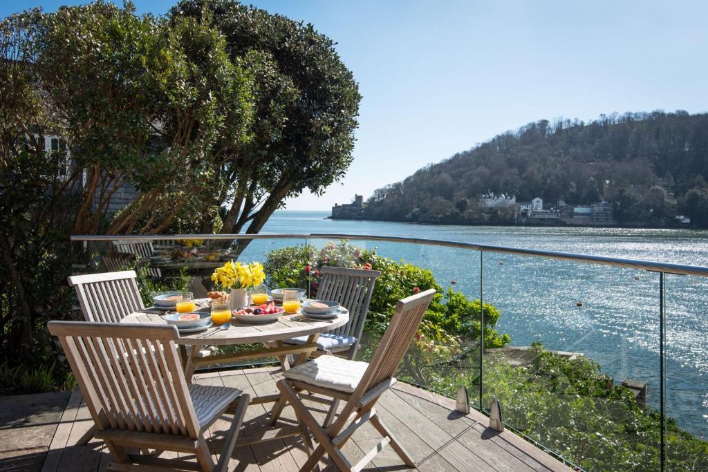 a table and chairs on a deck with a view of the water at The Edge in Dartmouth