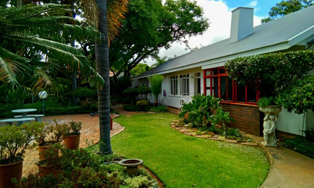 a house with a green yard with a palm tree at Lindekroon Guest House in Polokwane