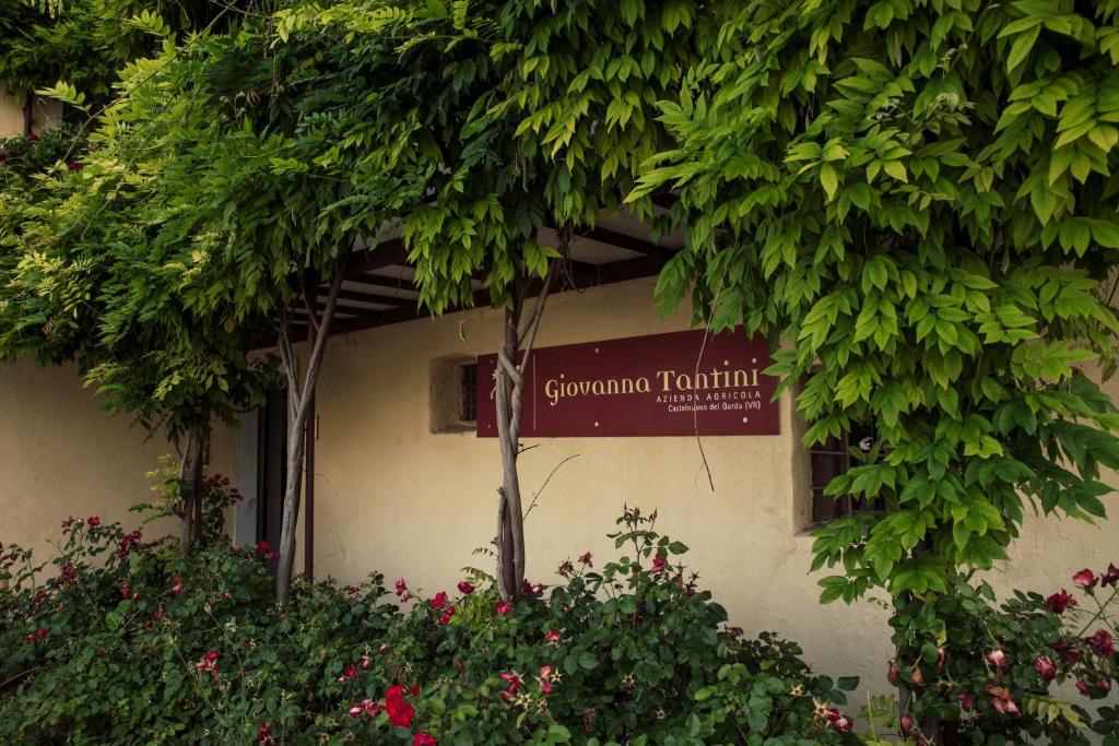 ein Schild an der Seite eines Gebäudes mit Bäumen und Blumen in der Unterkunft Agriturismo I Mischi in Castelnuovo del Garda