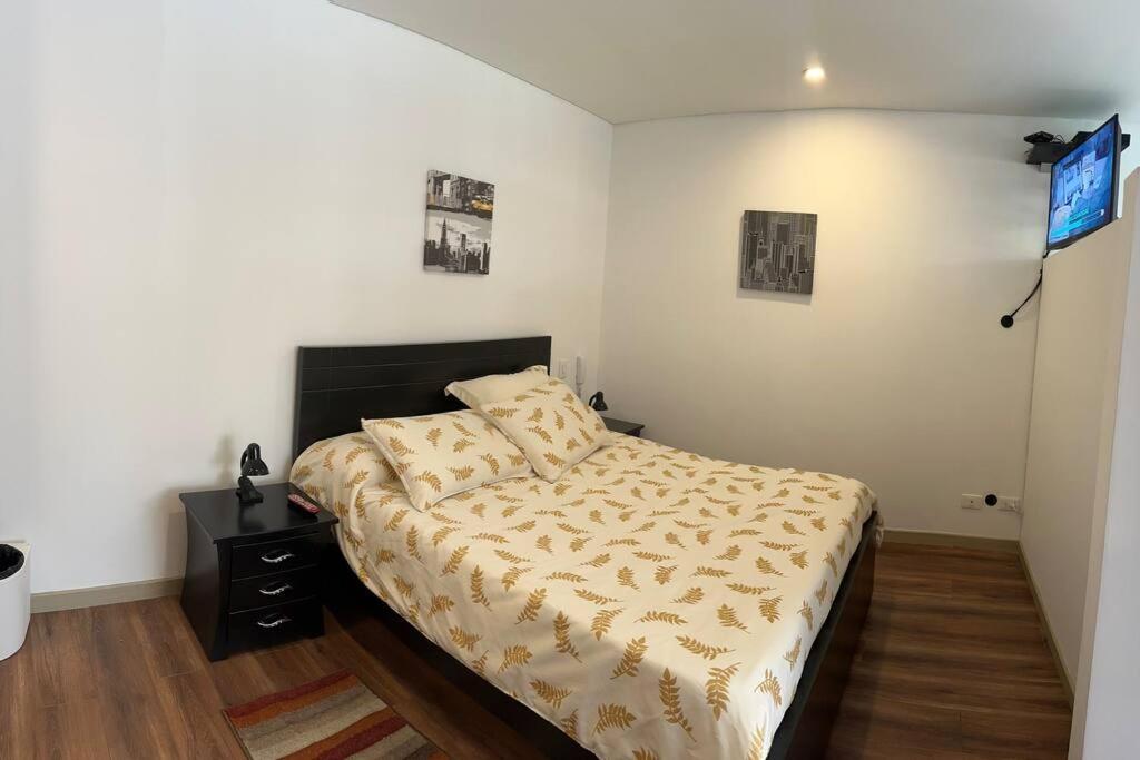 a bedroom with a bed and a television on the wall at Nice apartment independent in front business center in Bogotá