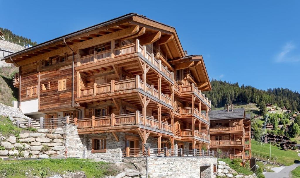 un grand bâtiment en bois avec des terrasses sur une montagne dans l'établissement Chalet Skyfall by Mrs Miggins, à Grimentz