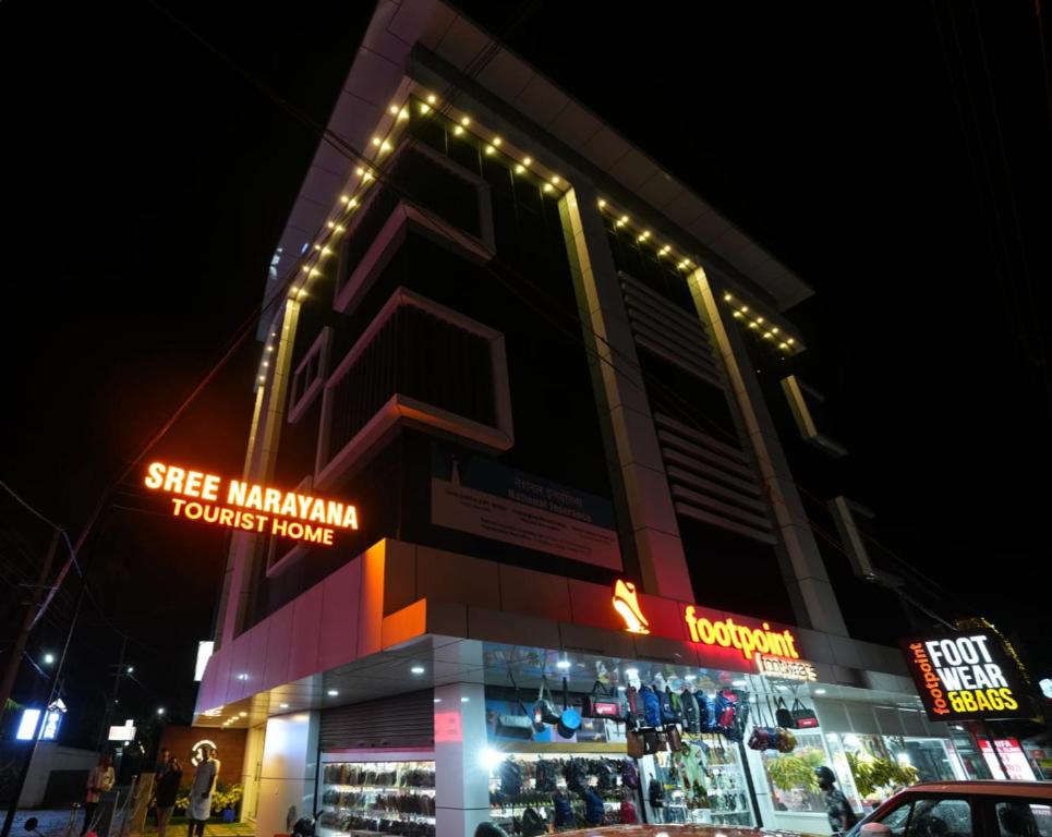 un bâtiment avec un magasin devant lui la nuit dans l'établissement SREENARAYANA TOURIST HOME, à Guruvāyūr