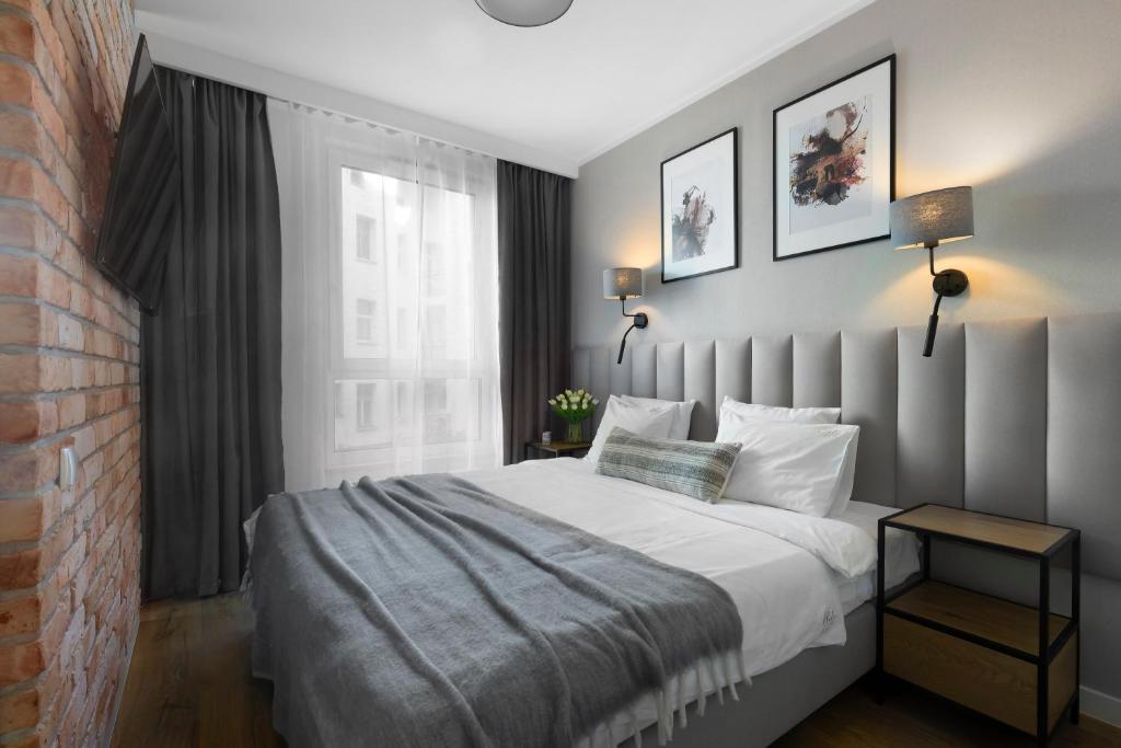 a bedroom with a large bed and a brick wall at Elite Apartments Chlebova Premium in Gdańsk