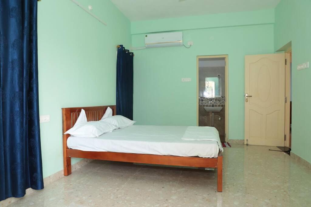 a bedroom with a bed with a blue wall and a door at Soundar villa in Puducherry