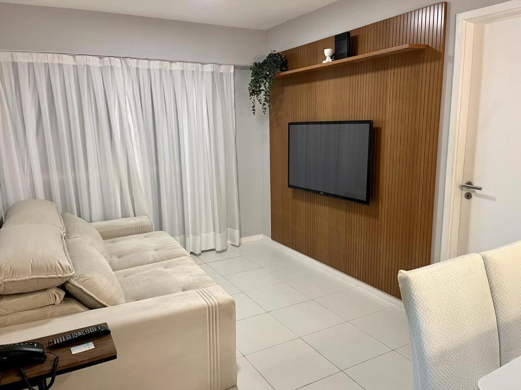 uma sala de estar com um sofá e uma televisão de ecrã plano em Apart Hotel próximo Barra da Tijuca e Rio Centro Manaca Flat A no Rio de Janeiro