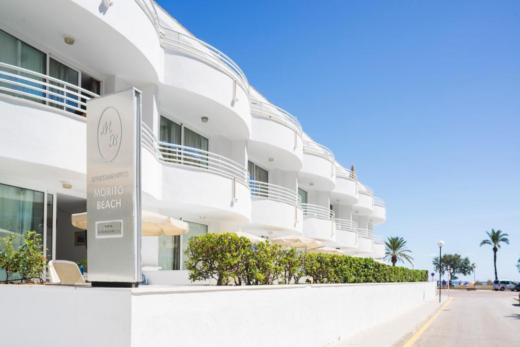 un edificio blanco con un cartel delante en Apartamentos Morito Beach, en Cala Millor