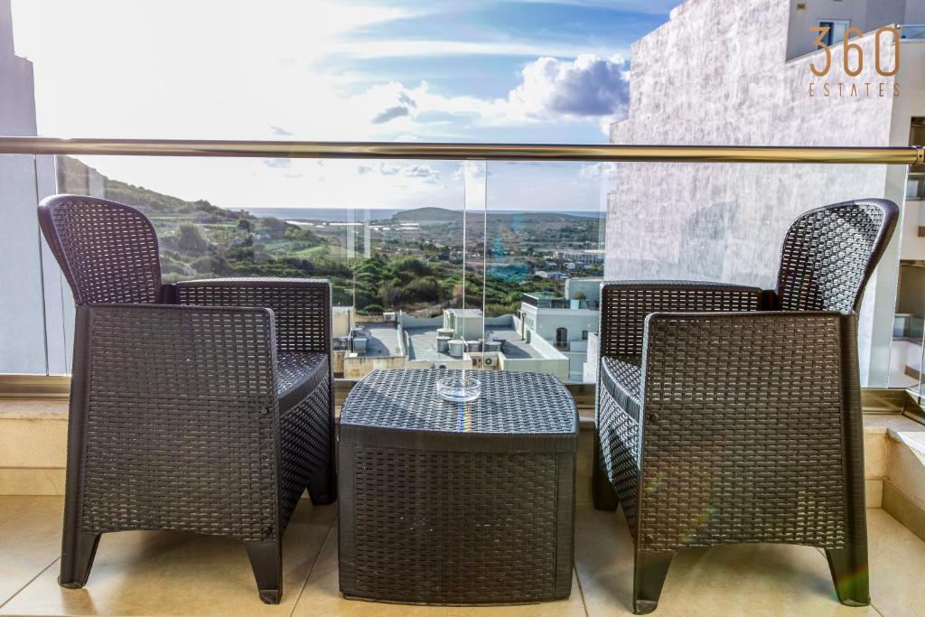 Duas cadeiras e uma mesa numa varanda com vista em Spacious, designer 2BR home with Captivating Views by 360 Estates em Mellieħa
