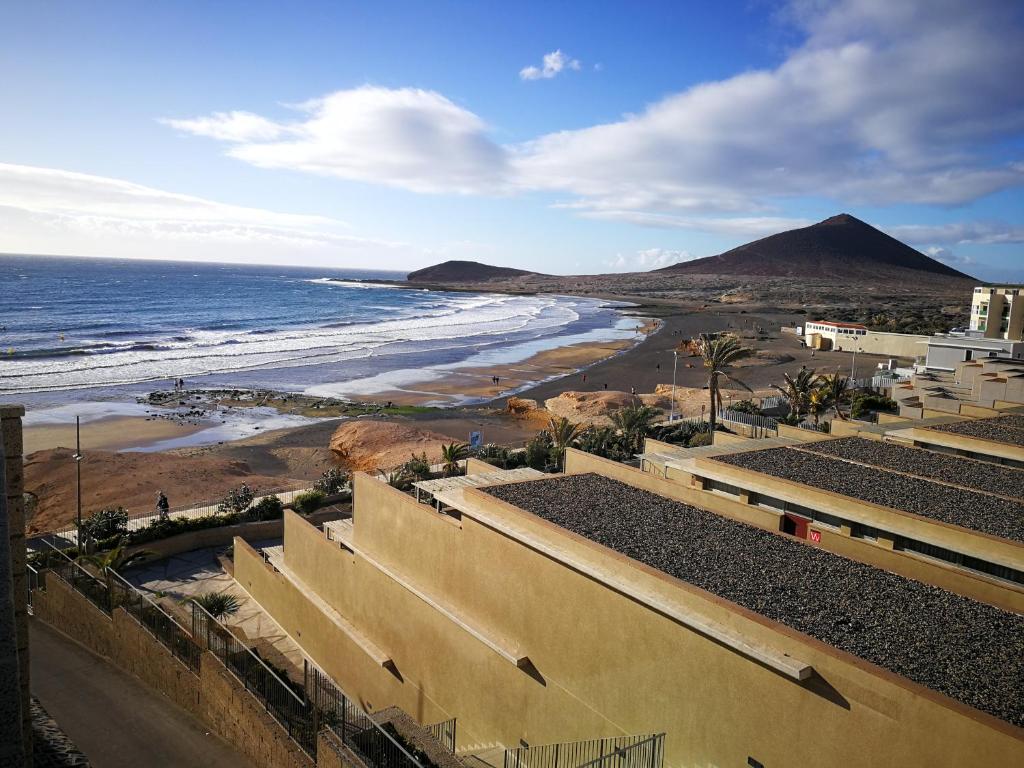 een uitzicht op een strand met een berg op de achtergrond bij Alquilaencanarias Duplex Playa del Médano in El Médano