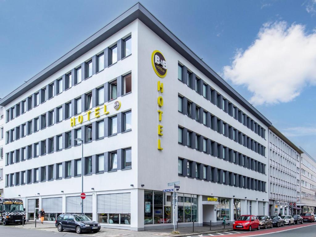 a large white building on a street with cars parked at B&B Hotel Nürnberg-Hbf in Nuremberg