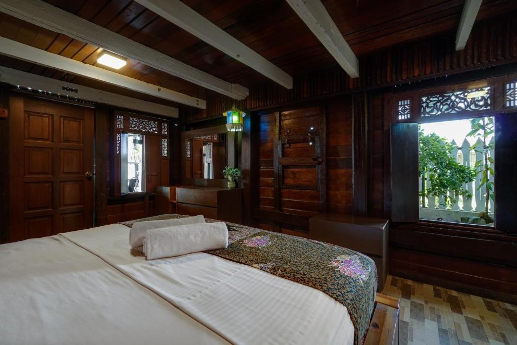 Schlafzimmer mit einem großen Bett mit Holzwänden und Fenstern in der Unterkunft Villapadu Desa in Kuala Terengganu