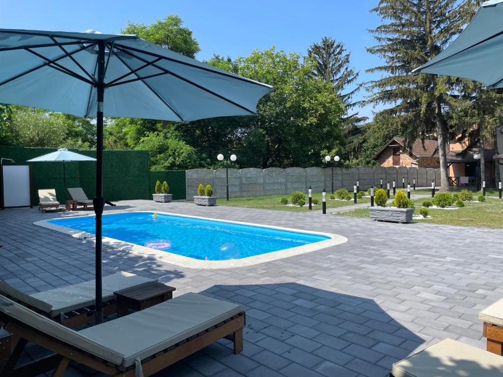 a swimming pool with an umbrella and two chairs and a table at Casa Mia Vrdnik in Vrdnik