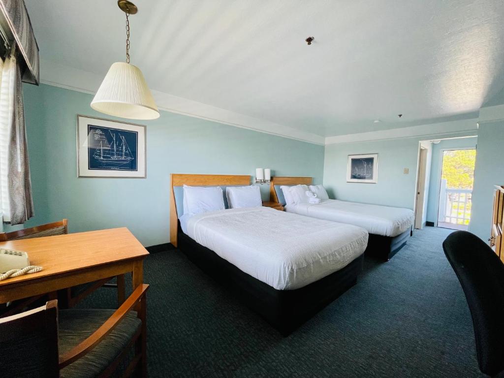 um quarto de hotel com duas camas e uma mesa em Seabird Lodge Fort Bragg em Fort Bragg