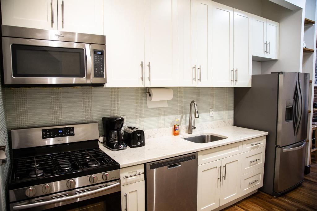 eine Küche mit weißen Schränken und Küchengeräten aus Edelstahl in der Unterkunft The Harlem Cascades in New York