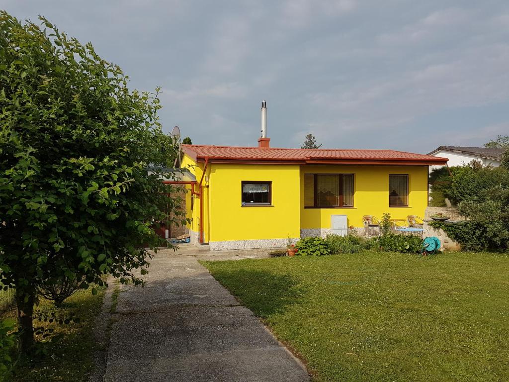 une maison jaune avec un toit rouge dans une cour dans l'établissement Ferienhaus Sonnenweg, à Sankt Andrä bei Frauenkirchen