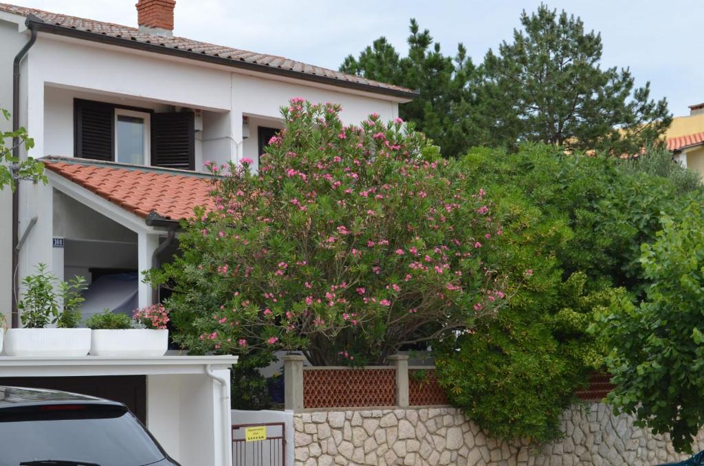 una casa con fiori rosa su un muro di pietra di Apartments Mili a Baška