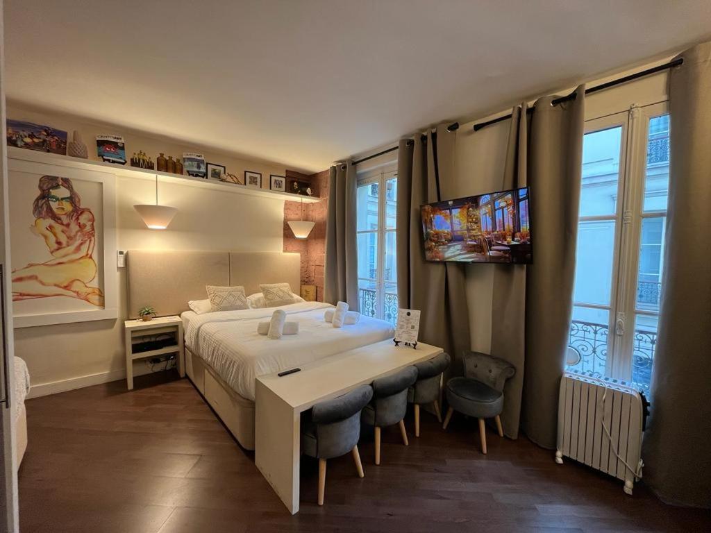 - une chambre avec un grand lit, un bureau et des chaises dans l'établissement Studio Pompidou - rue des Temples 3 places, à Paris