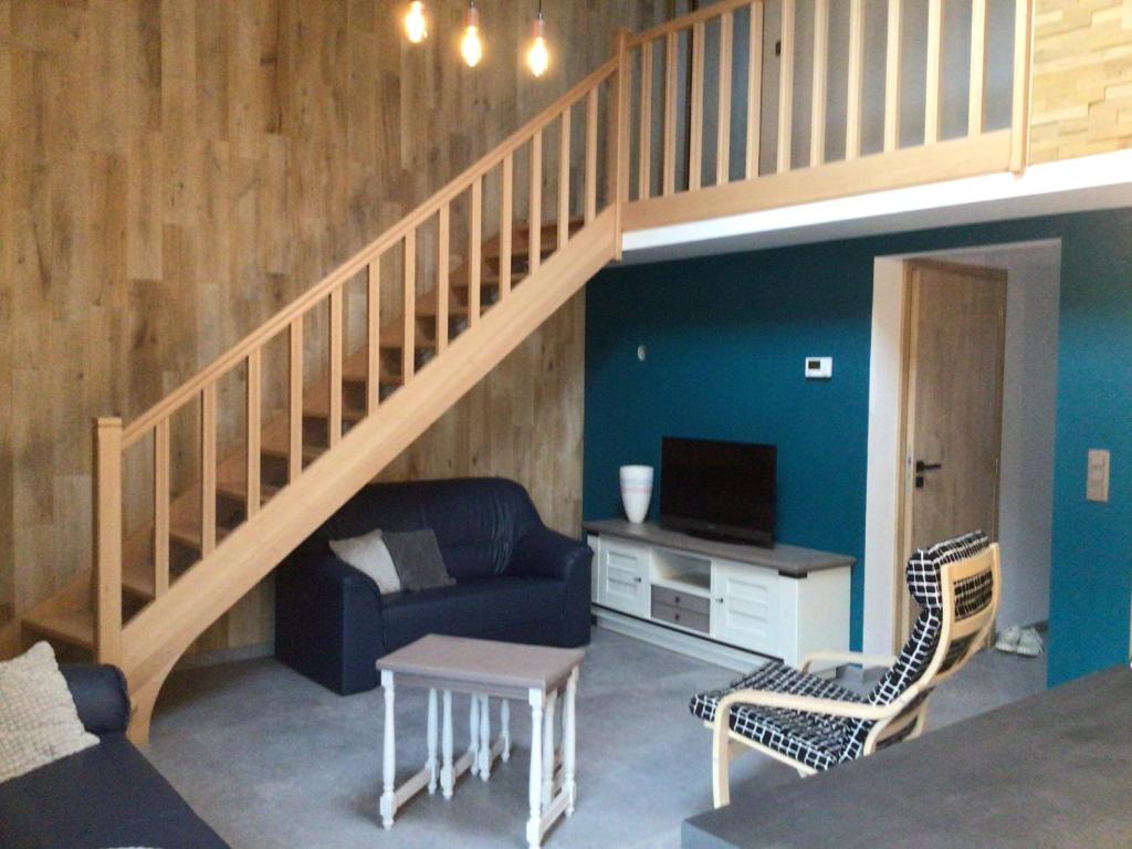 uma sala de estar com um sofá azul e uma escada em Chez Odile em Offagne