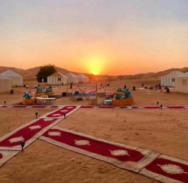 Merzouga luxurious Camps في مرزوقة: اطلالة على صحراء مع غروب الشمس في الخلفية