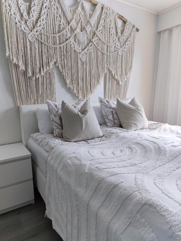 - un lit blanc avec des draps et des oreillers blancs dans l'établissement Laplands Hillside House, à Rovaniemi