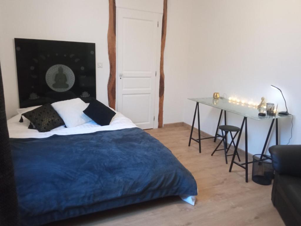 Schlafzimmer mit einem Bett, einem Tisch und einem Schreibtisch in der Unterkunft Chambre spacieuse et zen 