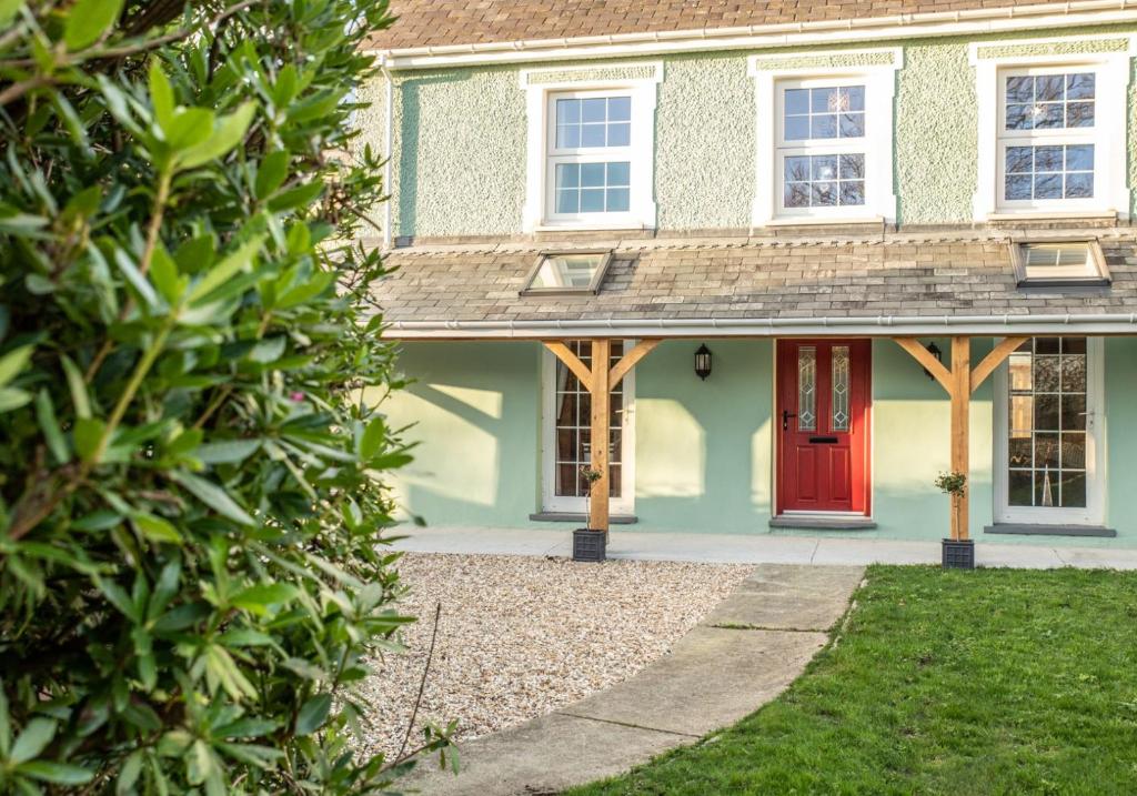 a house with a red door and a yard at Rhos y Gadair - an incredible farmhouse by the sea in Aberporth