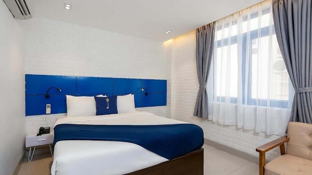 a bedroom with a blue and white bed and a window at Lucia Beach Hotel in Danang