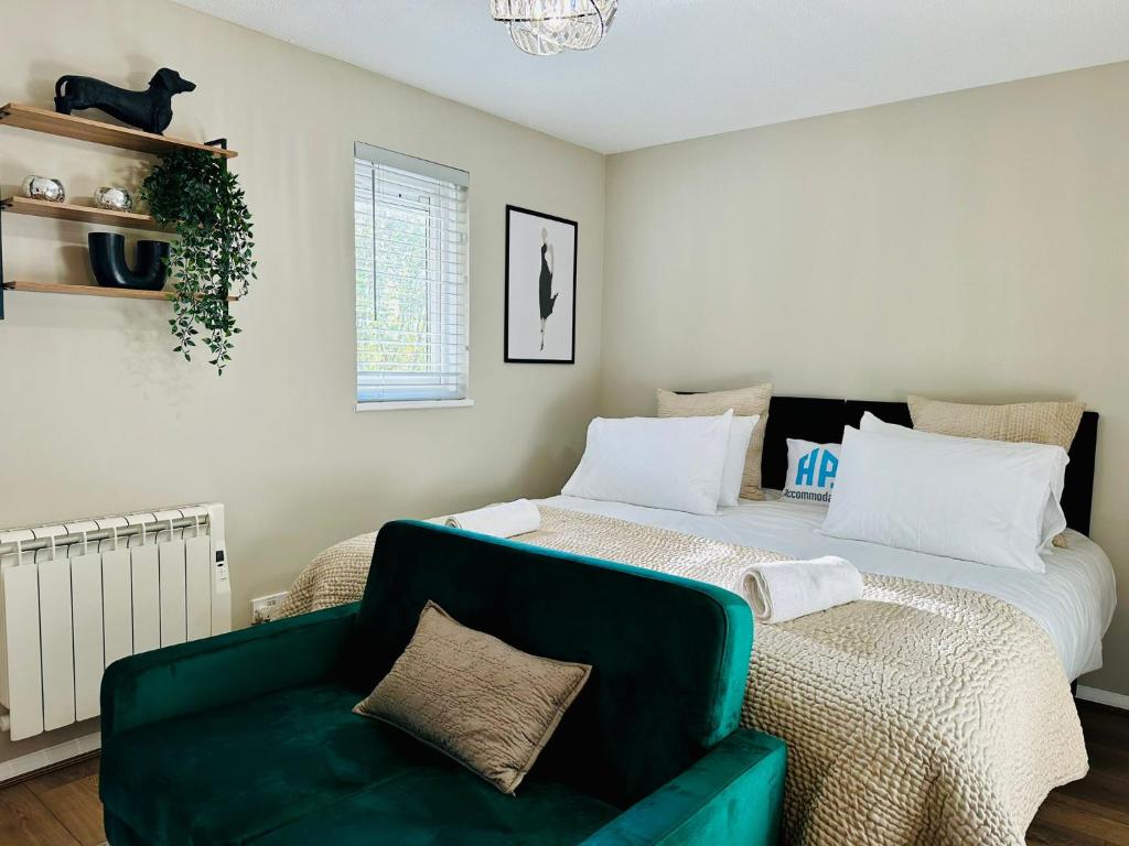 Charming Studio Apartment with Free Parking & WiFi in Milton Keynes by HP Accommodation في ميلتون كينز: غرفة نوم بسرير كبير واريكة خضراء