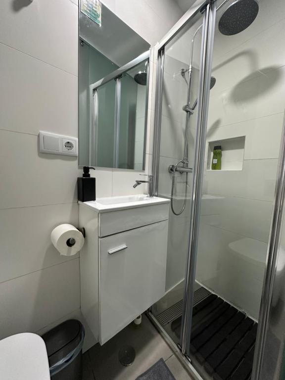 a white bathroom with a shower and a sink at Bonjóia Porto Guest House in Porto