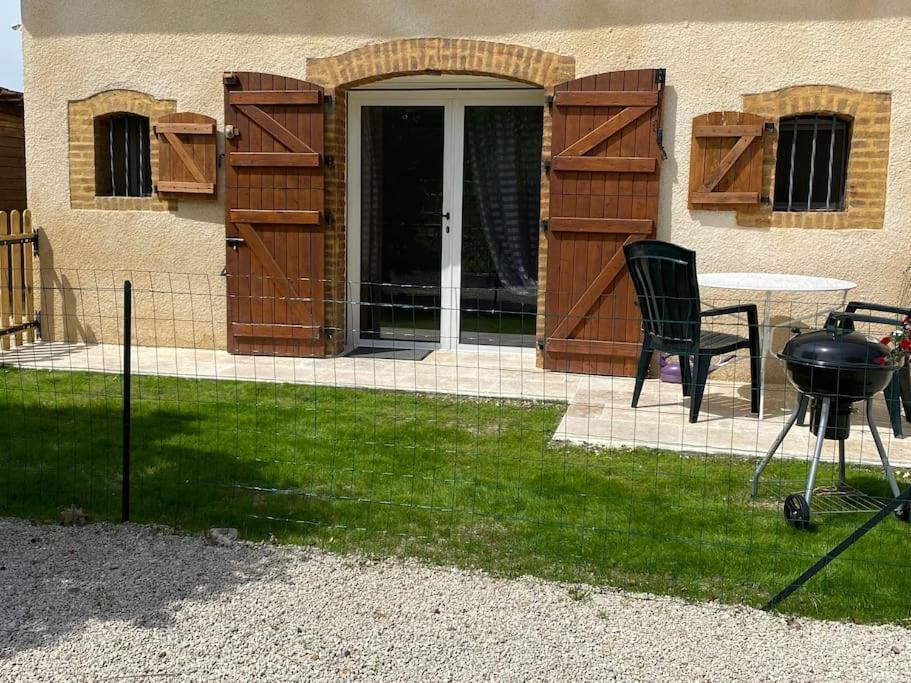 a grill and a table and a chair in a yard at Studio pour amoureux de la nature et des animaux in Auriébat