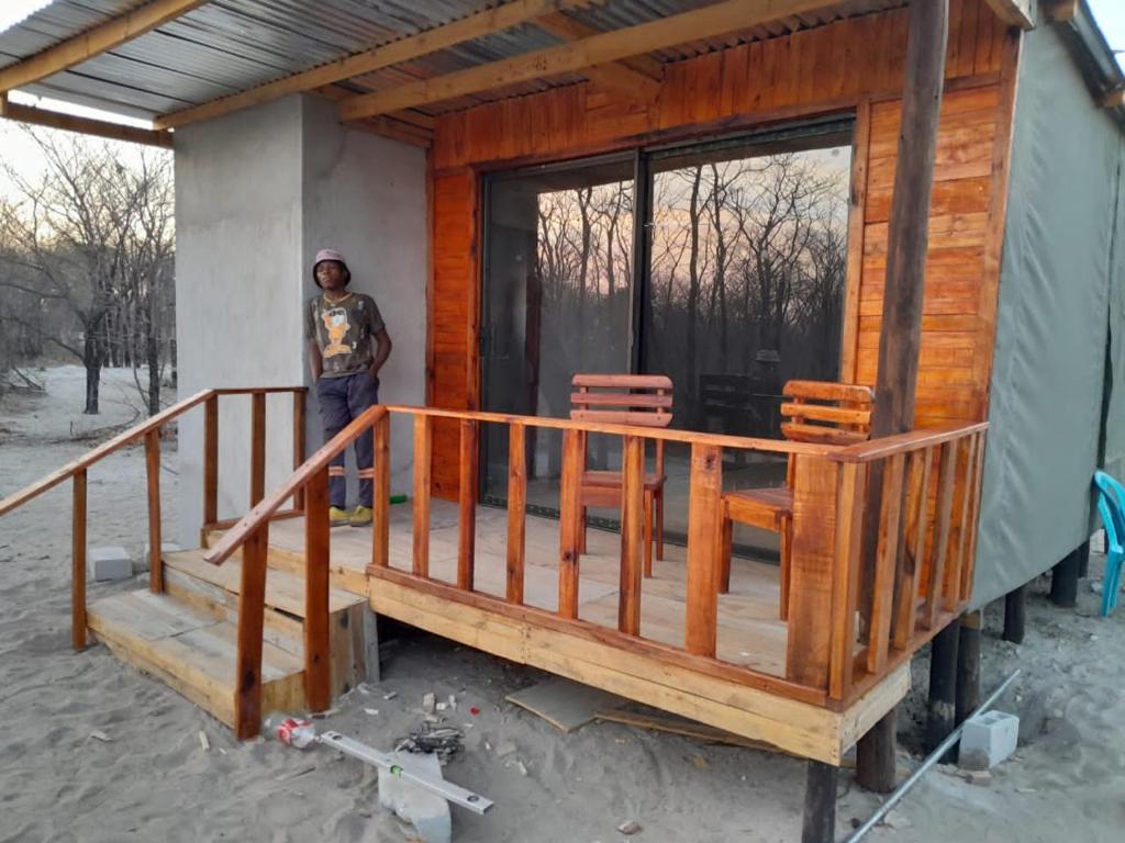 un hombre parado frente a una casa con un porche en Mokoka Rest Camp, en Nata