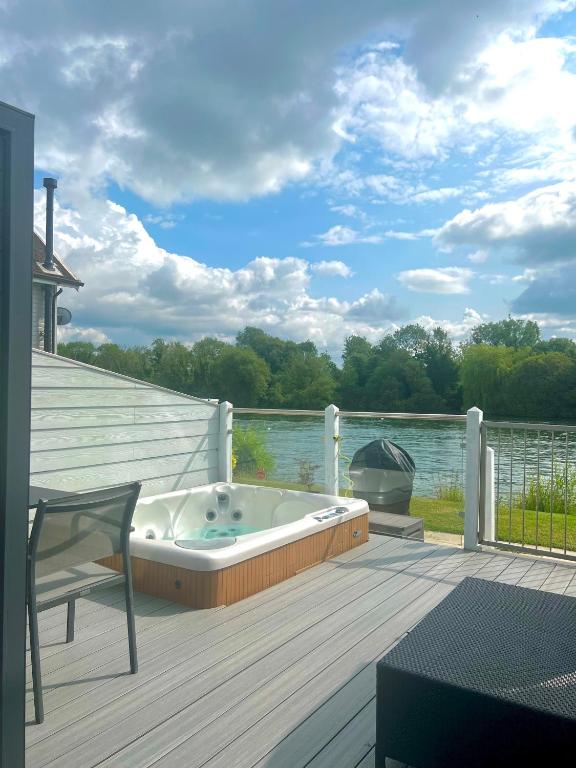 a hot tub sitting on a deck next to the water at Modern Cotswold Home w Hot Tub in South Cerney
