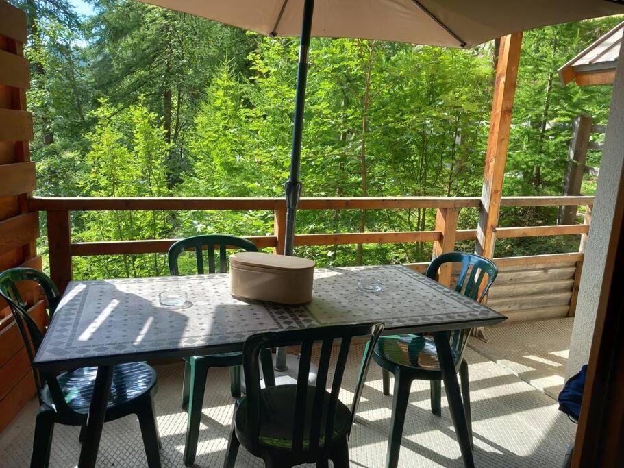 - une table et des chaises sur une terrasse couverte avec un parasol dans l'établissement T2 au pied des pistes, à Puy-Saint-Vincent