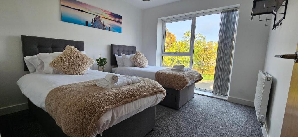 1 dormitorio con 2 camas y ventana grande en Whiterose Roundabout Apartment, en Doncaster