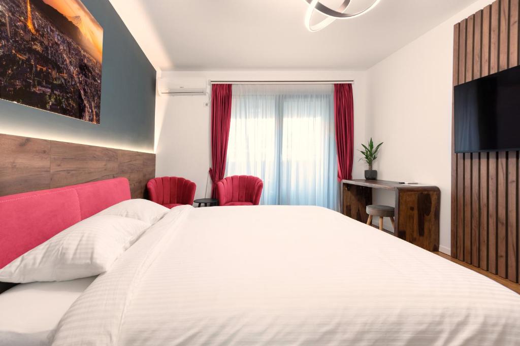 Schlafzimmer mit einem großen weißen Bett und roten Stühlen in der Unterkunft Pitesti Residence in Piteşti