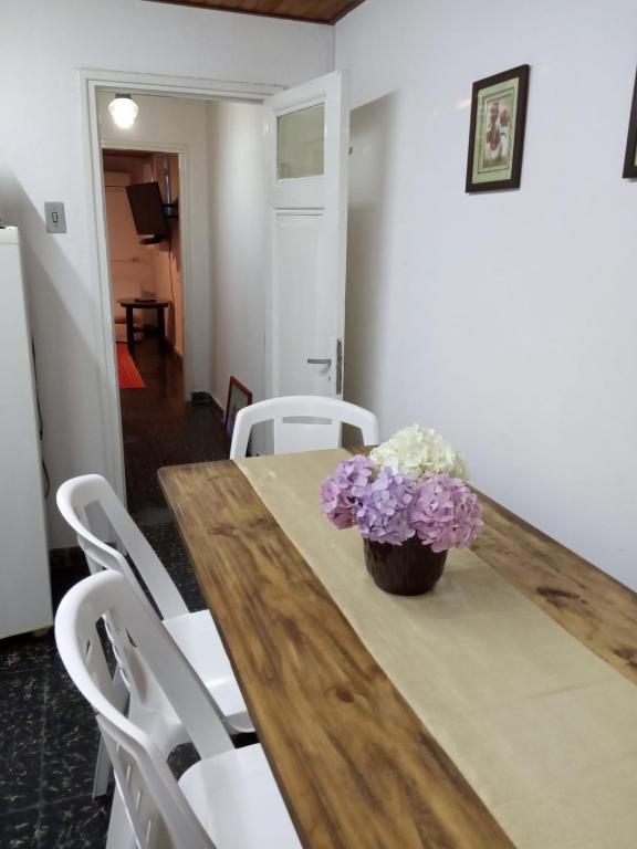 a wooden table with a vase of purple flowers on it at Casa Orión in La Paloma