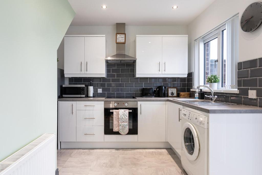 a kitchen with white cabinets and a dishwasher at Fully Refurbished North Belfast Home 2 in Belfast