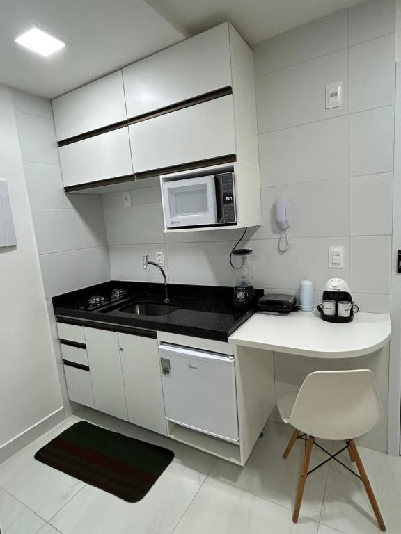 a white kitchen with a sink and a microwave at Melhores Flats - Tranquilo, pertinho do mar in João Pessoa