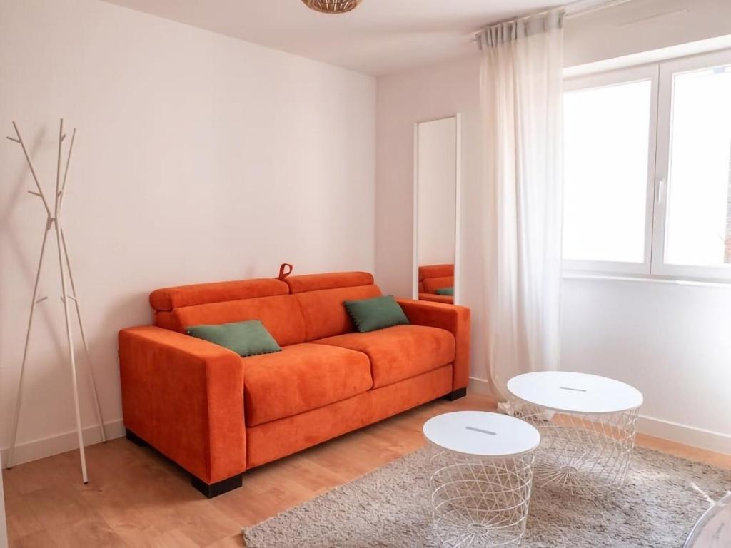 un sofá naranja en una sala de estar con ventana en Le Phalsbourg - Escapade citadine à Strasbourg en Estrasburgo