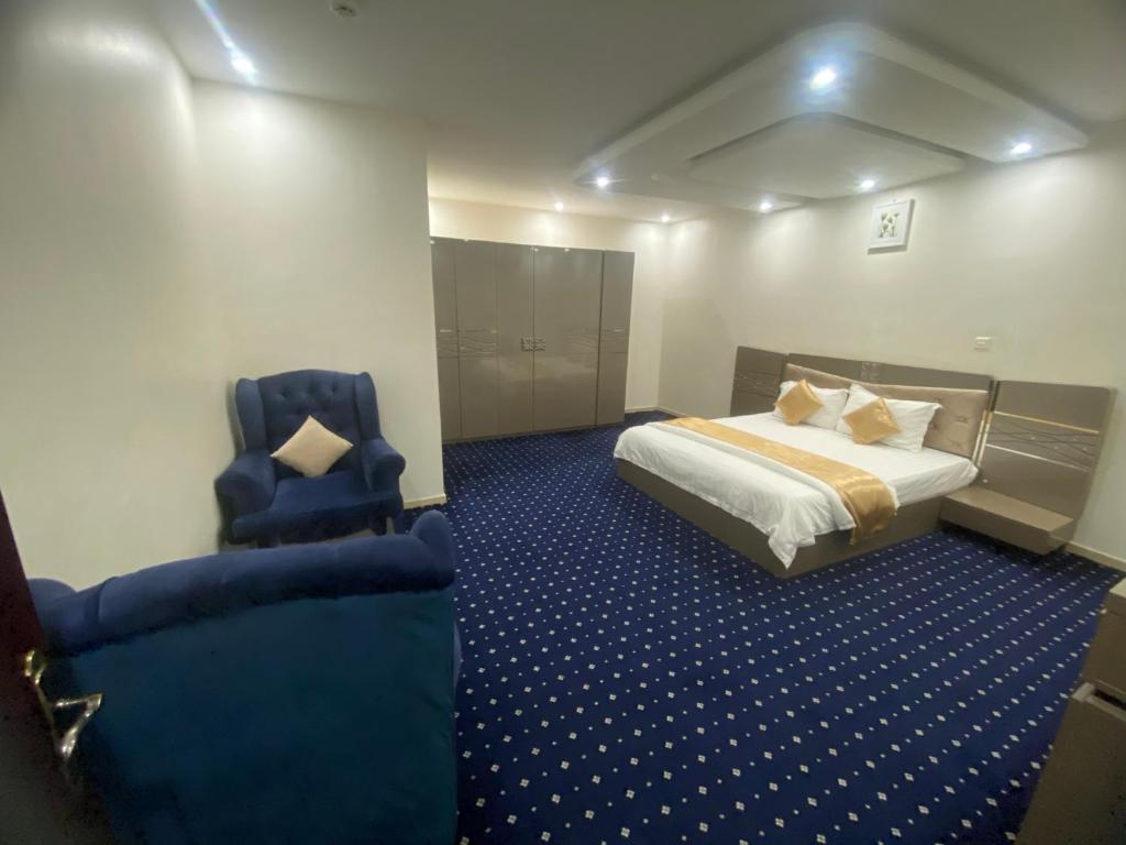 une chambre d'hôtel avec un lit et deux chaises bleues dans l'établissement فندق أسس التاج, à Abou Arish