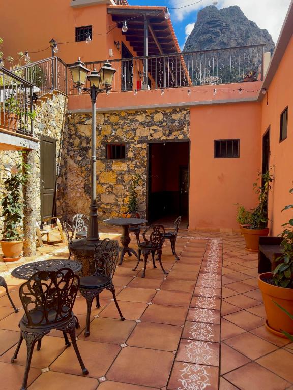 a patio with tables and chairs with a mountain in the background at Tamahuche Hotel Rural in Vallehermoso