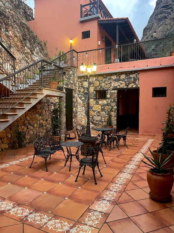 a patio with tables and chairs and a staircase at Tamahuche Hotel Rural in Vallehermoso