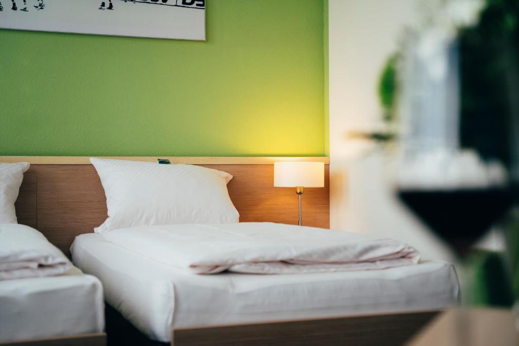 1 dormitorio con 2 camas y pared verde en business & conference Sporthotel Großwallstadt en Großwallstadt